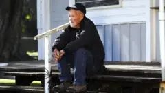 Charlie Hopkins sentado en la entrada de casa