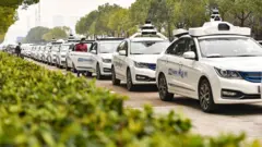 চীনের রাস্তায় চালক-বিহীন রোবট্যাক্সির সারি। প্রথমদিকে পরীক্ষামূলকভাবে এরা বিনা ভাড়ায় যাত্রী ওঠাচ্ছে।