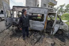 Un hombre junto a un vehículo incendiado en Jalud