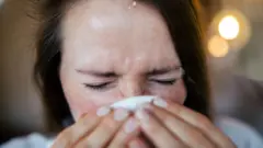 Uma mulher com os olhos fechados e um lenço no nariz.