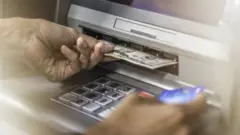 Pesin dey take money comot ATM.