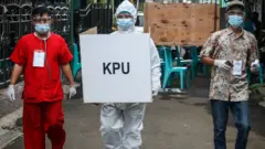 Petugas KPPS TPS 68 membawa kotak suara untuk mengunjungi pemilih pasien COVID-19 dengan status Orang Tanpa Gejala (OTG) di Pondok Maharta, Tangerang Selatan, Banten, Rabu (9/12)