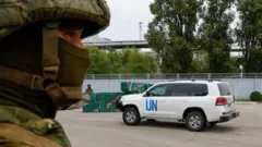 A car transporting members of the International Atomic Energy Agency (IAEA) expert mission drives past a checkpoint