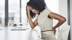 ቁጭ ብላ ወገቧን የያዘች ሴት