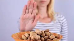 A woman refusing a bowl of peanuts