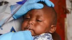 Un travailleur de la santé effectue un prélèvement nasal sur un nourrisson à Nairobi, au Kenya, en mai 2020.