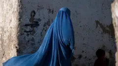 امرأة أفغانية ترتدي البرقع تمشي مع طفل في كابل في 28 أبريل/نيسان 2022