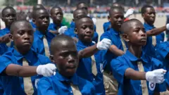 Some of students wey dey go free school for Ghana do march-past for dia Independence day