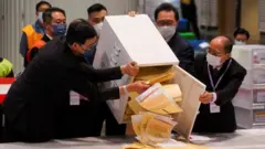 The chairman of Electoral Affairs Commission Barnabas Fung Wah and other members of EAC open the ballot box for the Legislative Council election at a vote counting centre, in Hong Kong, China 19 December 2021