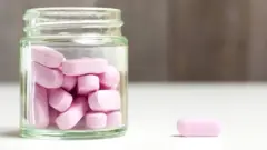 Un frasco y píldoras rosas