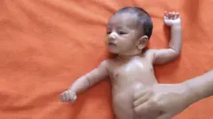 A baby having its stomach massaged