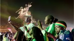 Supporters du Sénégal arborant les couleurs nationales au pied du monument de la renaissance africaine
