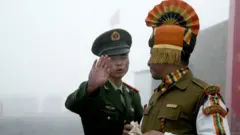 A Chinese soldier gestures as he stands near an Indian soldier on the Chinese side of the ancient Nathu La border crossing between India and China