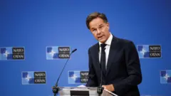 Mark Rutte Nato logolu bir kürsüde açıklama yaparken. 