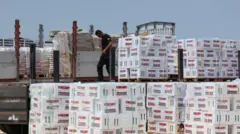 عامل يفرغ مساعدات إنسانية قرب معبر إيريز/بيت حانون، شمال قطاع غزة - 1 أيار/مايو 2024