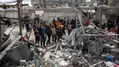 فلسطينيون يبحثون عن مفقودين تحت أنقاض المباني المدمرة عقب الغارات الجوية الإسرائيلية في خان يونس