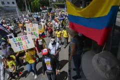 Marcha em rua na Colômbia com pessoas usando bandeiras