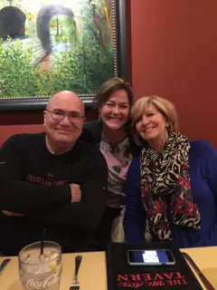 Kevin, Deb y Val sonríen en una mesa de un restaurante.