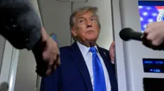 Trump luce corbata azul y asoma la cabeza por una puerta del Air Force One para hablar con los periodistas a su regreso de las reuniones del G7 en Canadá