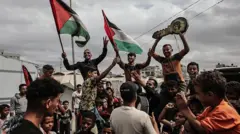 غزيون يرفعون الأعلام الفلسطينية ويحتلفون بإبرام المرحلة الأولى من وقف إطلاق النار بين إسرائيل وحماس