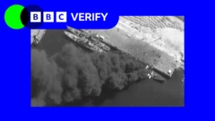 卫星影像显示伊朗一座港口内停泊的三艘船只，其中一艘可见浓烟窜出。