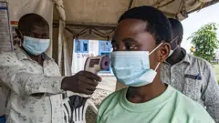 Pessoa tendo sua temperatura verificada com termômetro sem contato na fronteira entre Uganda e a República Democrática do Congo, no dia 18 de maio de 2026