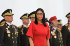 Delcy Rodriguez, presidente da Venezuela, em vestido vermelho, rodeada de militares da alta patente uniformizados.
