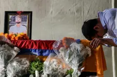 इजरेलबाट विपिन जोशीको पार्थिव अवशेष नेपाल आइपुगेपछि शवपेटिका र जोशीको तस्बिरनजिकै सम्मान व्यक्त गर्दै एक व्यक्ति