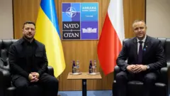 Зеленський і Навроцький сидять у кріслах навпроти один одного на полях саміту НАТО в Анкарі. Позаду них розміщені прапори України та Польщі, а між прапорами — логотип саміту НАТО 2026. Між співрозмовниками стоїть невеликий столик із пляшками води.