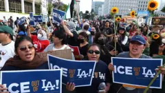 Decenas de personas con letreros que dicen "Fuera ICE de Los Ángeles". 