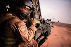 Un soldat de la force Barkhane tient une arme dans un hélicoptère