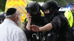 Бойцы специального подразделения полиции в шлемах преграждают дорогу мужчине в белой рубашке и кипе