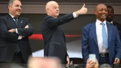 O presidente da Concacaf, Victor Montagliani, o presidente da Fifa, Gianni Infantino, e o presidente da Caf, Patrice Motsepe, assistem das bancadas à final da Copa do Mundo Masculina da Fifa de 2026, no MetLife Stadium, em Nova York (Estados Unidos)