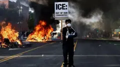 Un manifestante sostiene un cartel que dice "ICE: Fuera de nuestras comunidades" durante las protestas de principios de junio en Los Ángeles, California.
