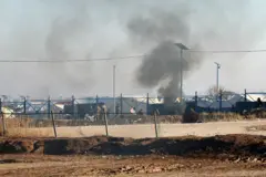 Suriye güvenlik güçleri El Hol Kampı'nda görülüyor. Önlerinde teller, arkalarında çadırlar var. Duman çıkıyor. (21 Ocak 2026) 