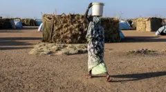 لاجئة سودانية تسير بين خيام مخيم أوري كاسوني بتشاد، في نوفمبر/تشرين الثاني الماضي.