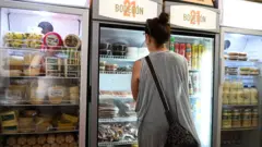 Mulher escolhe produtos em uma pequena loja de Havana