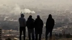 जंग शुरू होने के तीन दिन बाद सोमवार को तेहरान में उठते धुंए को देखते लोग