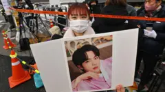 Seorang penggemar memegang foto anggota BTS, Jin, di depan unit pelatihan militer di Yeoncheon pada 13 Desember 2022, sebelum Jin memulai wajib militernya.