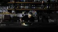 Homem trabalha em um restaurante no escuro em Madri.