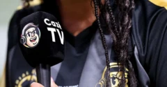 Pessoa com cabelos trançados segurando um microfone da CazéTV