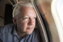 Julian Assange no avião, após deixar prisão no Reino Unido 