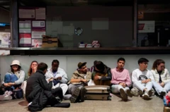 Pessoas sentadas no chão em aeroporto