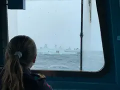 Recrutas observando pela janela outros navios de guerra da Otan a bordo da fragata norueguesa Otto Sverdrup