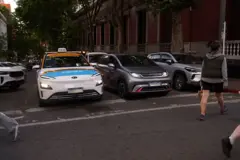 Pessoa atravessa a rua em frente a um táxi e um carro de passeio, ambos elétricos, no centro de Montevidéu