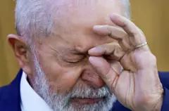 Lula sério com a mão no rosto