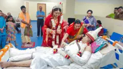 হাসপাতালের বেডে শুয়ে আছেন সড়ক দুর্ঘটনায় আহত আনন্দ সাহা। ফুলের মালা হাতে পাশে দাড়িয়ে নববধূ অমৃতা সরকার। 