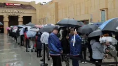 Fãs esperam em fila, com guarda-chuvas, para assistir à final da 5ª temporada de Stranger Things no Egyptian Theatre Hollywood, em 31 de dezembro de 2025, em Los Angeles, Califórnia.