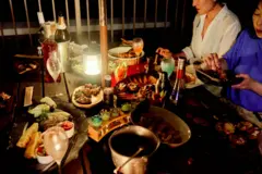 Uma mesa com vários pratos e um grupo de amigos reunido para jantar.