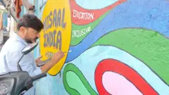 Un hombre pinta un mural en una pared en una comunidad marginal de la ciudad de Bombay.